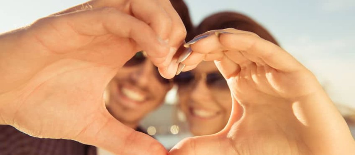 52410143 - happy romantic couple in love gesturing a heart with fingers