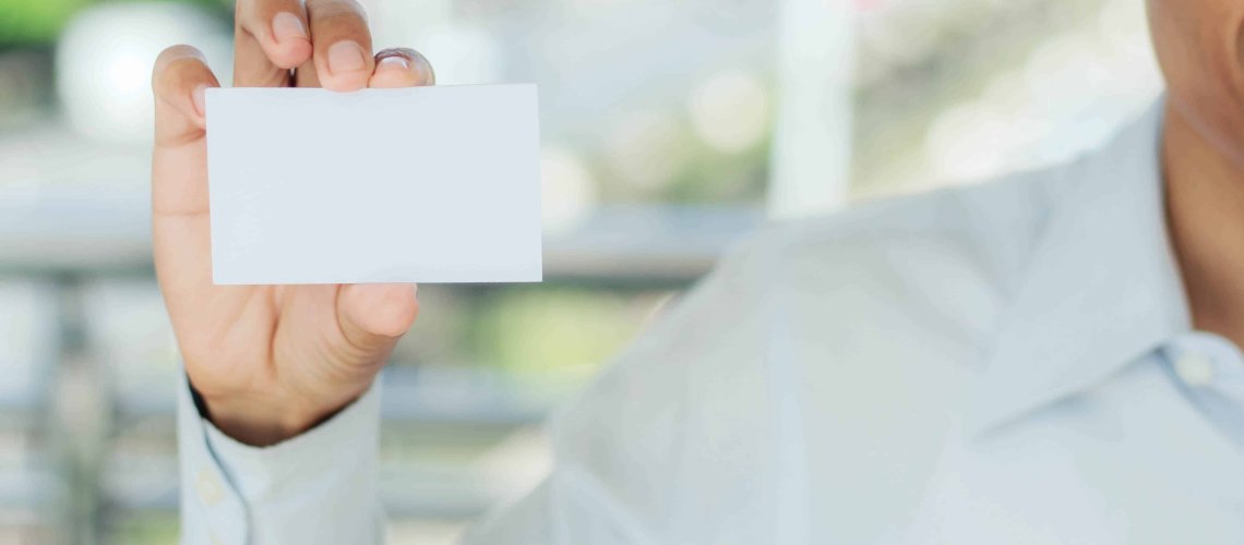 Young man holding a white business card.